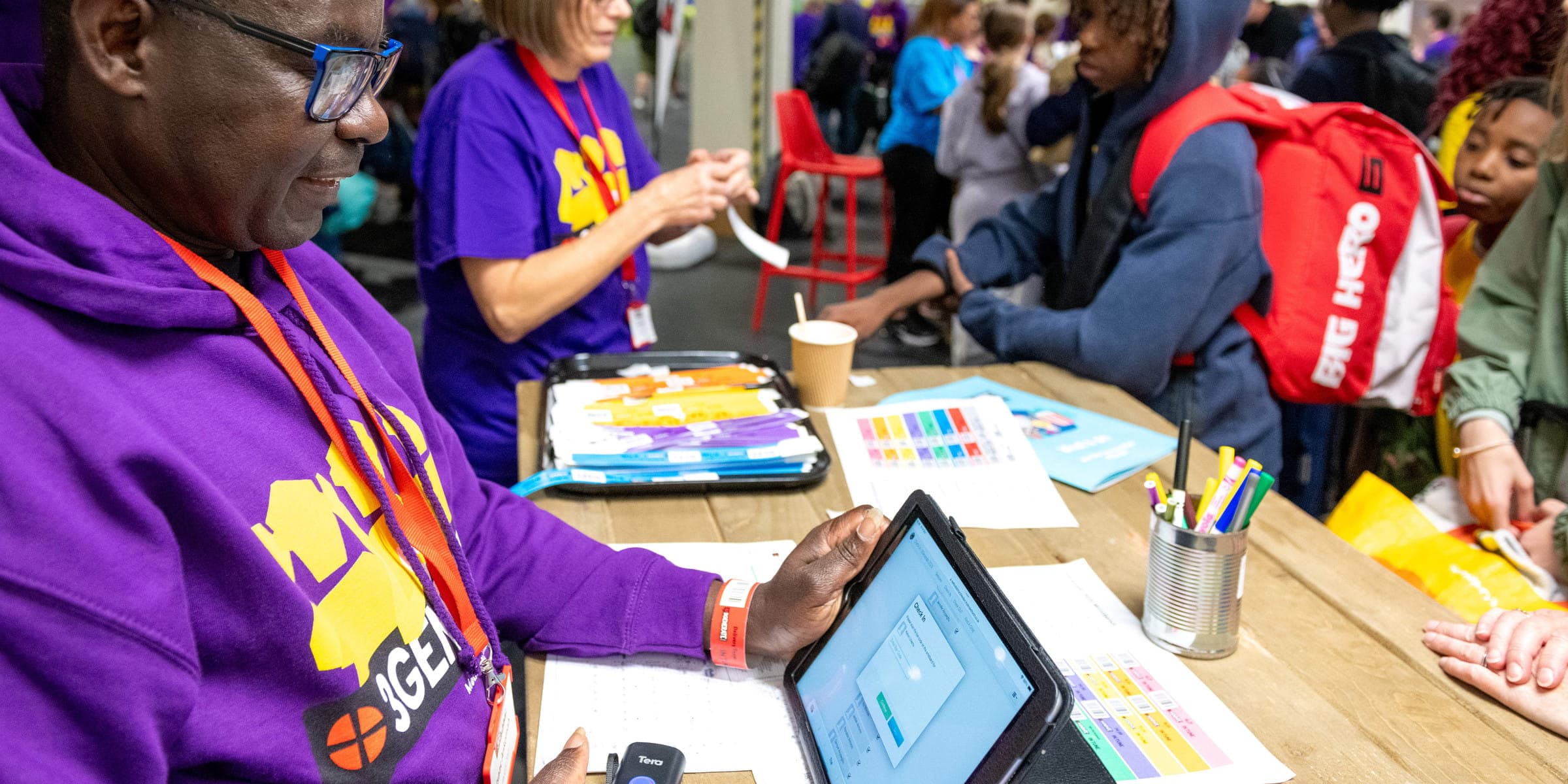 Volunteers checking young people in on a tablet at 3Generate